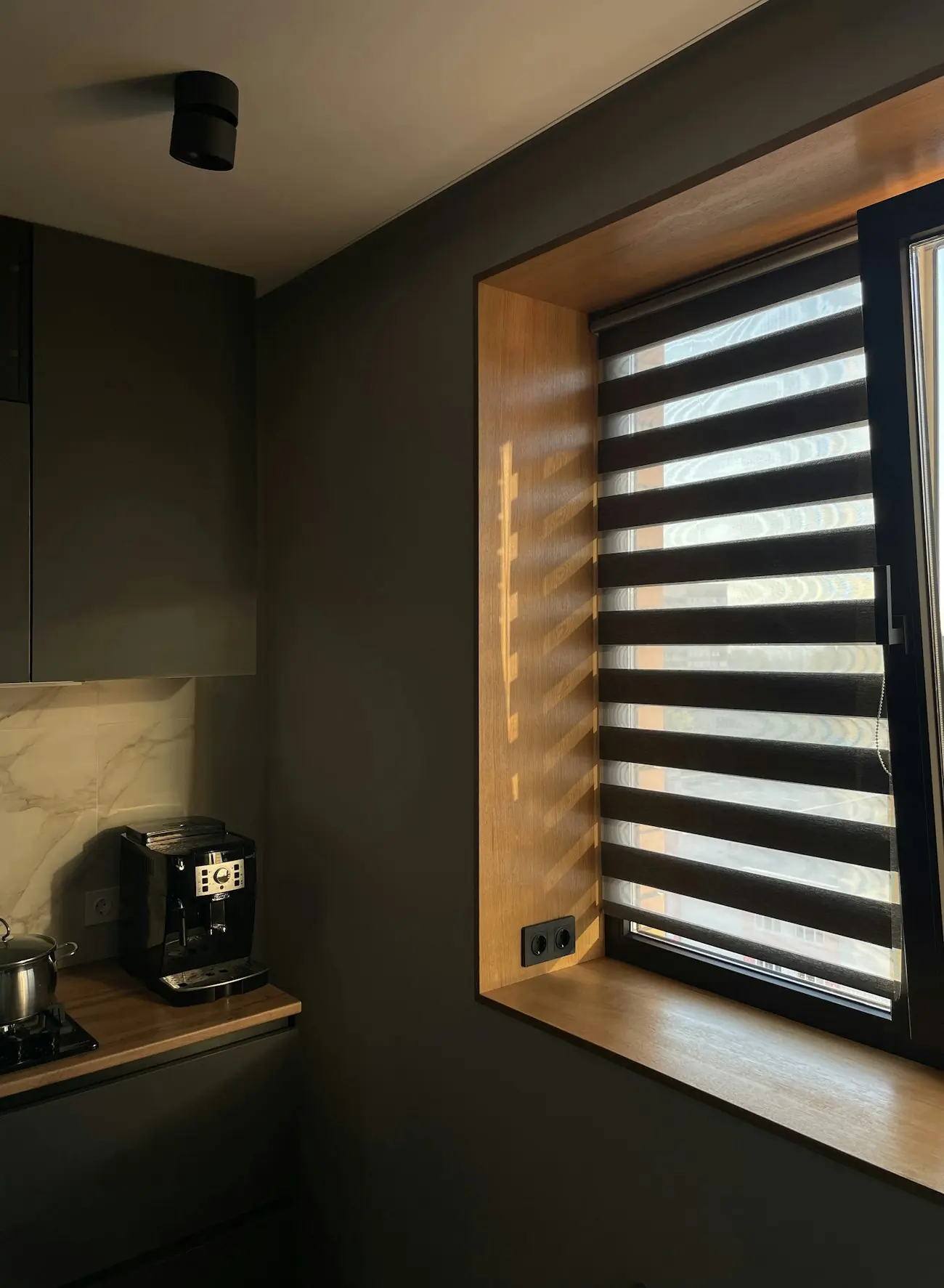 Mutfak penceresinde ışığı bantlar hâlinde geçiren zebra perde